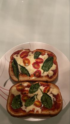 two slices of bread with cheese and spinach on them are sitting on a plate