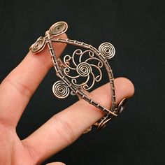 a hand holding a piece of jewelry in it's palm with an intricate design