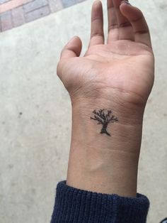 a person with a small tree tattoo on their wrist is holding up her hand to the camera