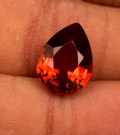 a close up of a person's hand holding an orange diamond