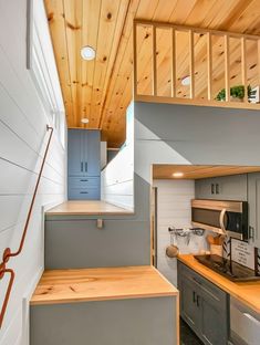 a kitchen with wooden ceiling and stairs leading up to the upper floor, along with gray cabinets