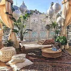 an outdoor living area with couches, tables and hanging lanterns on the wall above