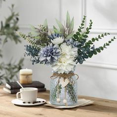 a vase filled with flowers sitting on top of a table next to a cup and saucer