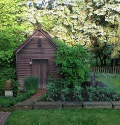 a small wooden shed sitting in the middle of a lush green field