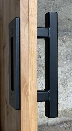 a close up of a door handle on a wooden door with concrete steps in the background