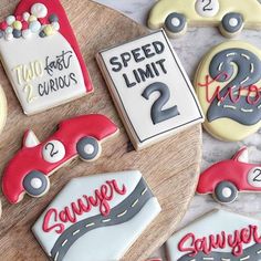 decorated cookies with numbers and cars are on a wooden tray next to a sign that says speed limit