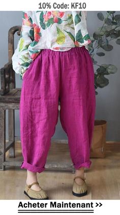 a woman standing in front of a chair wearing pink pants and a white shirt with flowers on it