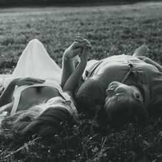 black and white photograph of a woman laying on the grass with her head in her hands