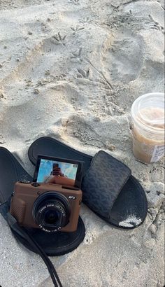 a camera sitting on top of a pair of sandals next to a cup of coffee