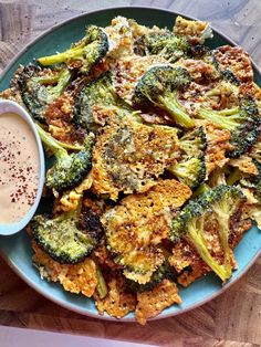 broccoli florets on a blue plate with dipping sauce in the middle