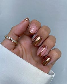 a woman's hand with gold and pink nail polish