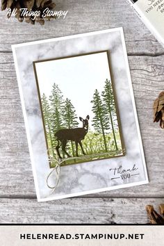 a card with an image of a deer in the woods and pine cones around it