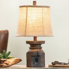 a table lamp sitting on top of a wooden table next to a bowl and potted plant