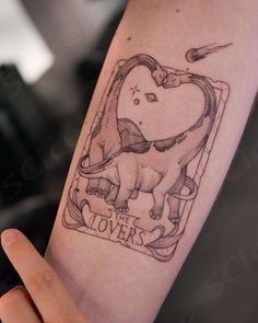 a person with a tattoo on their arm holding up a small heart shaped object in the shape of a trilops