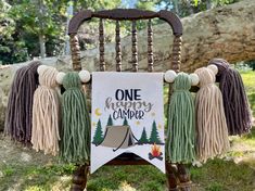 a wooden chair with tassels and a sign that says one happy camper