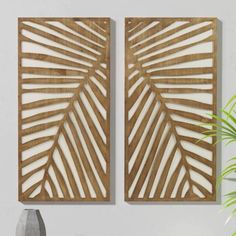 two wooden wall art pieces sitting on top of a table next to a potted plant