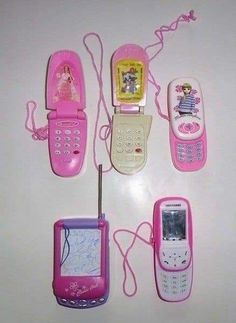 several cell phones are lined up next to each other on a white surface with pink cords