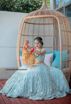 a woman in a blue dress is sitting on a swing chair and holding something up to her face