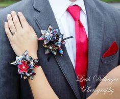 a man in a suit and red tie with two flowers on his lapel, both wearing matching bracelets