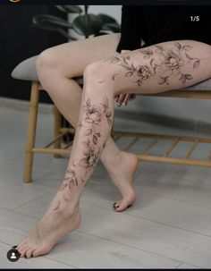 a woman sitting on top of a chair with her legs covered in floral tattoo designs