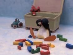 a penguin sitting on the ground next to toys