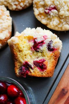 muffins with cranberries and powdered sugar are on a baking sheet