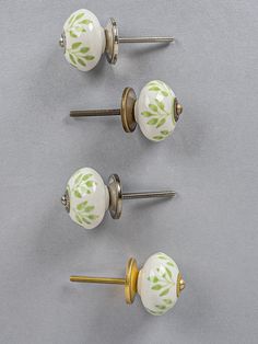 three white knobs with green leaves on them and two screws in the middle