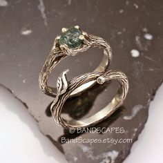 The top of the ring resembles Gandalf's staff. And set into the top is a raw, uncut natural sapphire from Montana. The color is teal: blue with a hint of green, and weighs 1.90ct. This stone is facet-grade material so VERY transluscent. Its beautiful. The engagement ring is made of twig and branch forms that securely clasp the stone. The stone is set so that it is visible from every angle, and able to capture light. Sitting snug next to that, is a matching twig wedding band. The band nests into Rough Stone Engagement Ring, Raw Stone Engagement Rings, Twig Wedding Band, Green Sapphire Engagement, Green Sapphire Engagement Ring, Gandalf, Montana Sapphire, Green Sapphire, Stone Engagement Rings