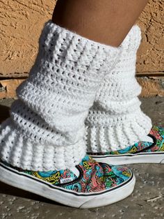 someone wearing white crocheted slippers with colorful designs on them and their feet