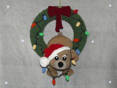 a teddy bear hanging from a christmas wreath ornament with lights on it's head