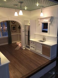 an open kitchen and living room with hardwood floors, white cabinets and lights on the ceiling