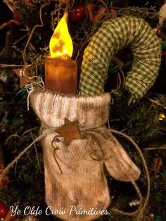 a christmas ornament with a lit candle and mitten on top of it