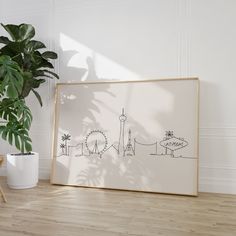 an art work is displayed on the floor next to a potted plant