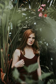 a beautiful young woman standing in front of some plants