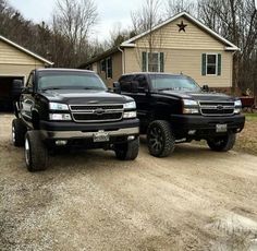 two black trucks parked in front of a house