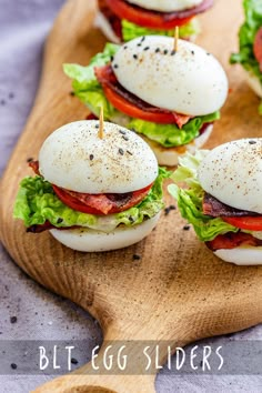 small sandwiches with bacon, lettuce and tomato on a wooden cutting board next to a spoon