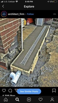 a drain pipe laying on the ground next to a brick wall and some concrete pipes