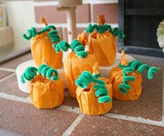 small pumpkins are sitting on the floor next to a fire place with green pom - poms