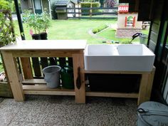 a white sink sitting under a window next to a wooden table with two buckets on it