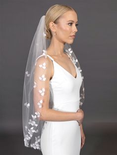 a woman wearing a wedding veil with white flowers on the side and one layer of tulle