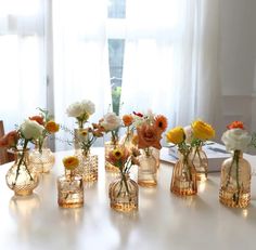 there are many small vases with flowers in them on the table next to each other