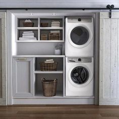 a washer and dryer sitting in a room next to some shelves with baskets