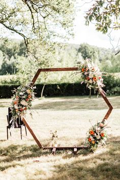 an outdoor ceremony setup with flowers and greenery in the shape of a hexagonal frame