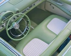 the interior of an old car with green leather and white stitching on the floor