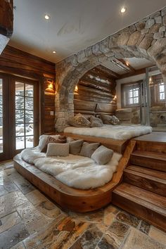 a large bed sitting in the middle of a room next to a stone wall and windows