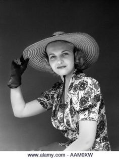 a woman in a hat and dress sitting on a chair with her hands behind her head