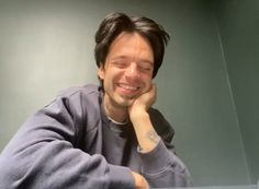 a man sitting at a table with his hand on his chin and looking to the side