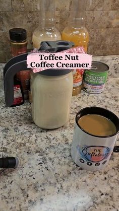 a coffee mug sitting on top of a counter next to a blender and cups