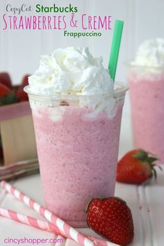 there is a strawberry milkshake with whipped cream on top and strawberries in the background