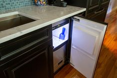 an open refrigerator in a kitchen next to a sink